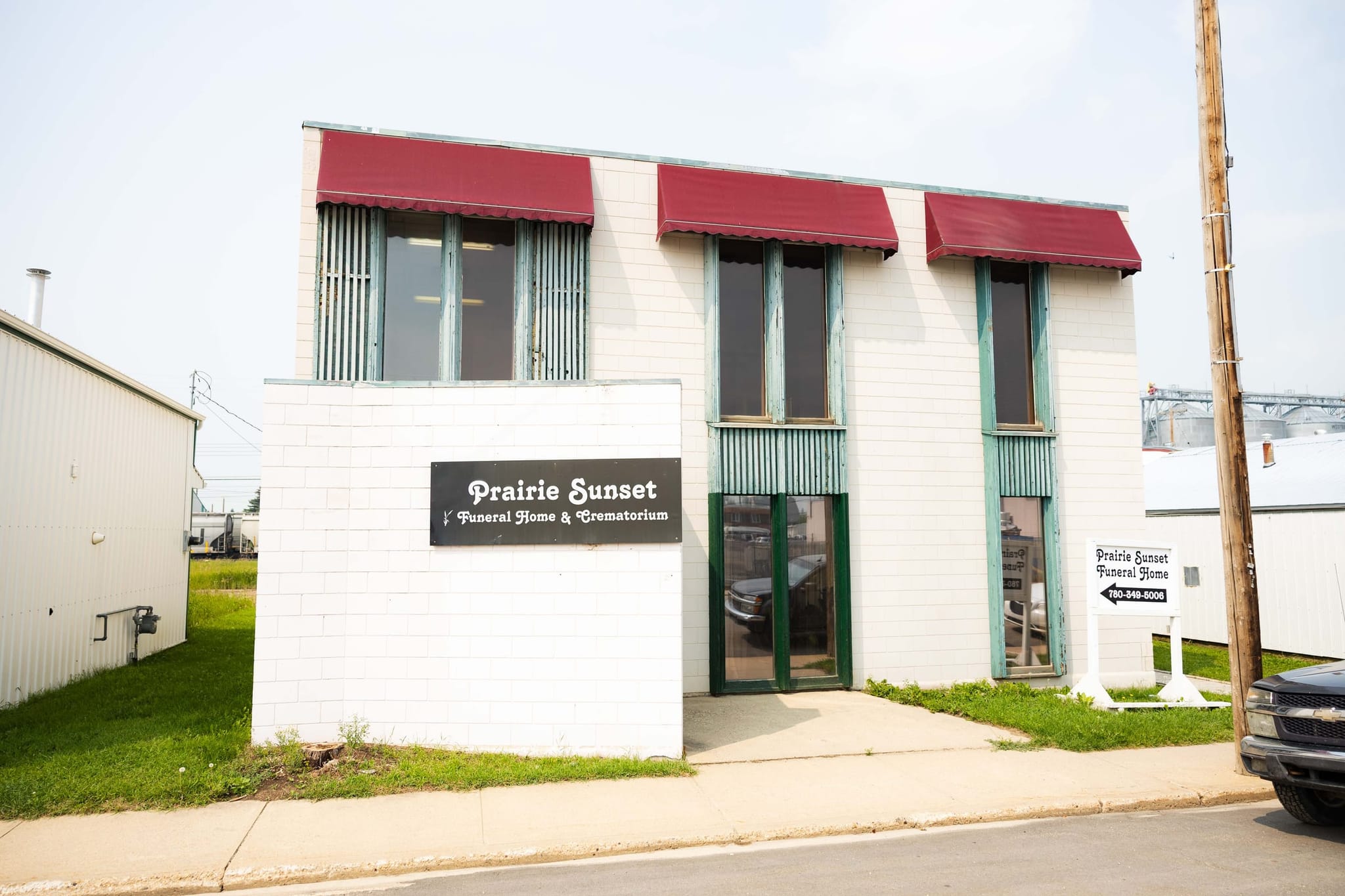 Prairie Sunset Funeral Home on 107 Street in Westlock: a white two-storey building with red awnings, its sign reading Prairie Sunset Funeral Home & Crematorium